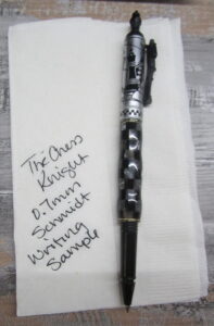 The Mistril Mechanisms Chess Knight pen - a black and silver checkerboard pen with a writing sample